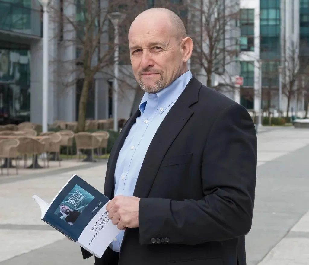 Dr. Klaus-Jürgen Wolf with his book on operational change in mid-sized companies